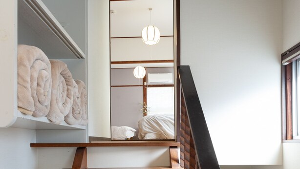 A wooden staircase with a modern design, leading to a room with a large mirror and a hanging light fixture. - Hakone no Yado (Hakone)