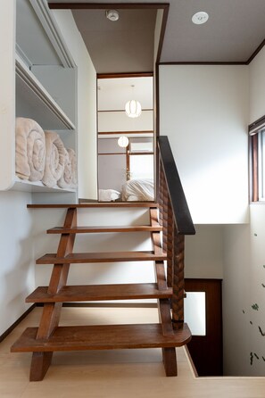 A wooden staircase with a modern design, leading to a room with a large mirror and a hanging light fixture. - Hakone no Yado (Hakone)