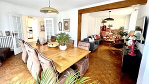 A spacious living room with a wooden dining table, comfortable seating, and a large plant. - L'âme Voyageuse, Raffinée, 2-8 Pers, Plages à 15min (Baye)
