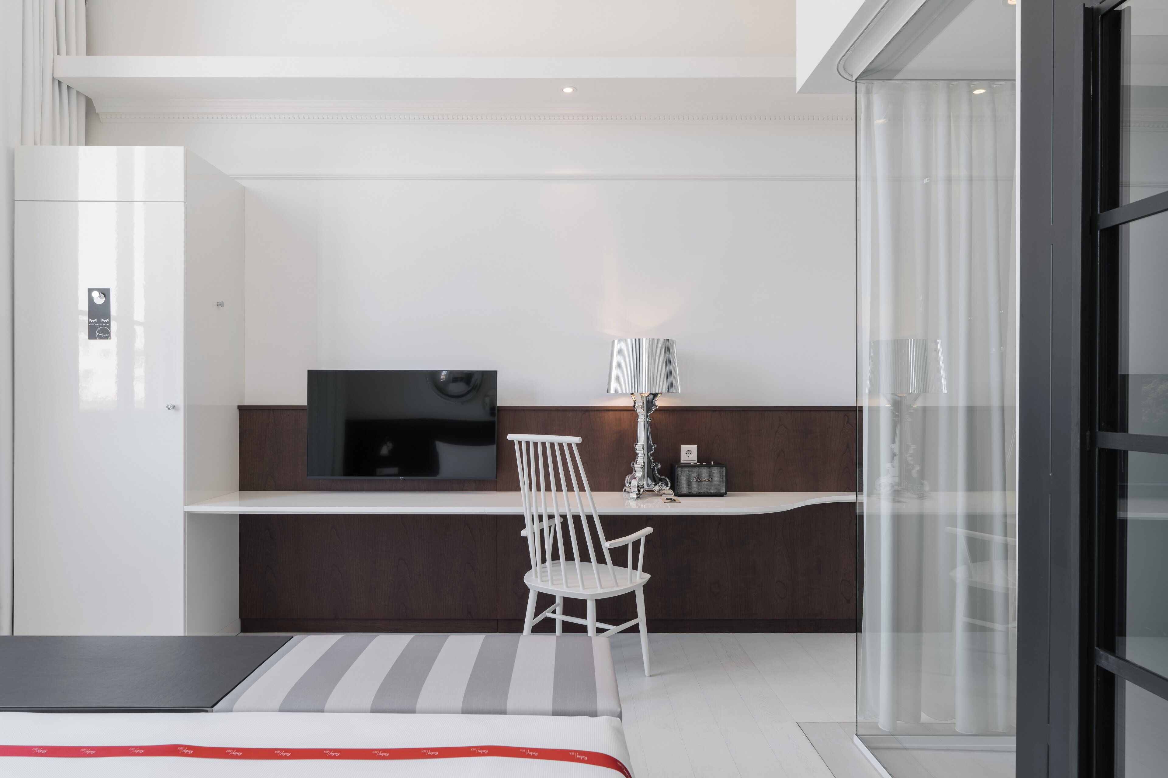 Una habitación de hotel moderna con cama, escritorio, silla, televisor y lámpara.