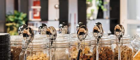 Una exhibición de alimentos con varios frascos de nueces y semillas, un letrero que indica el camino al jardín, y una lámpara de techo decorativa.