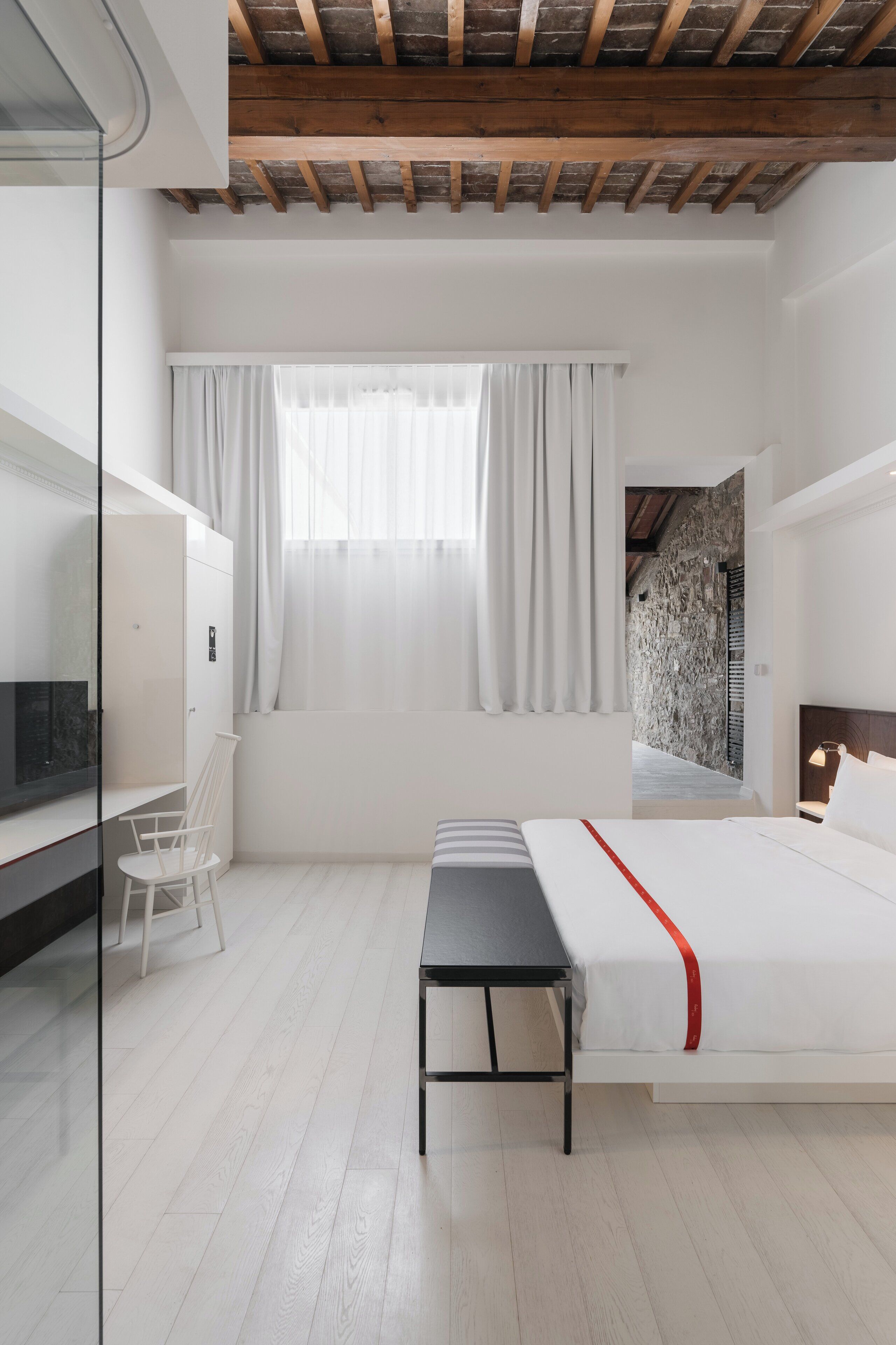 A modern bedroom with a bed, bedside table, and a mirror.