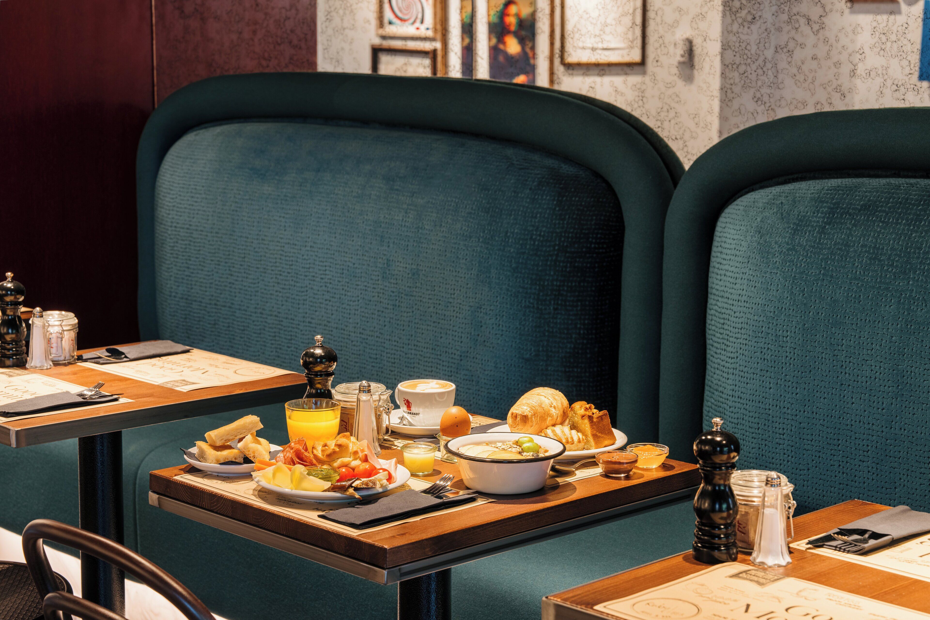 Mesa de desayuno lista con croissants, huevos y jugo de naranja en una habitación de hotel.