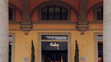 Un edificio con un'ampia entrata ad arco, un cartello con su scritto "Ruby" e due vasi con piante ai lati.
