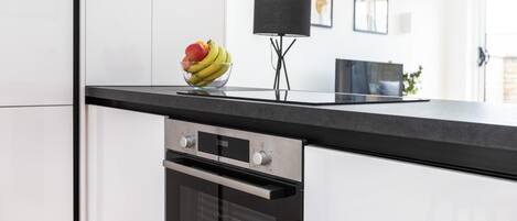 Una cocina moderna con armarios blancos, encimera negra y horno empotrado.