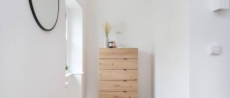 A minimalist room with a wooden dresser, a mirror, and a small plant on the dresser.