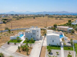 A modern building with a swimming pool, surrounded by greenery and a clear view of distant mountains. - Lilu Villa 1 With Private Pool and Seaview (Kos)