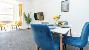 Un comedor con una mesa blanca, sillas azules y una planta en maceta.