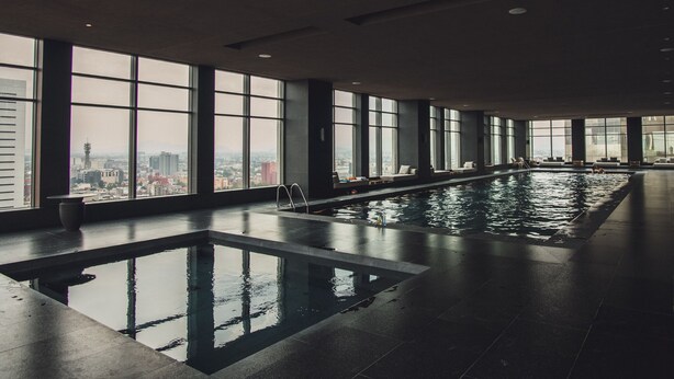 Ein überdachter Pool mit großen Fenstern und Blick auf die Stadt.