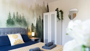 A bedroom with a bed, a wardrobe, a nightstand, and a wall mural.