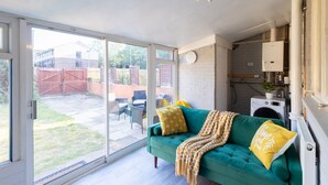 A room with a green sofa, a yellow throw blanket, and a white washing machine.