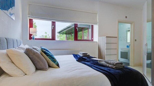 Ein Schlafzimmer mit Bett, Kissen, einem Fenster und einem Kleiderschrank.