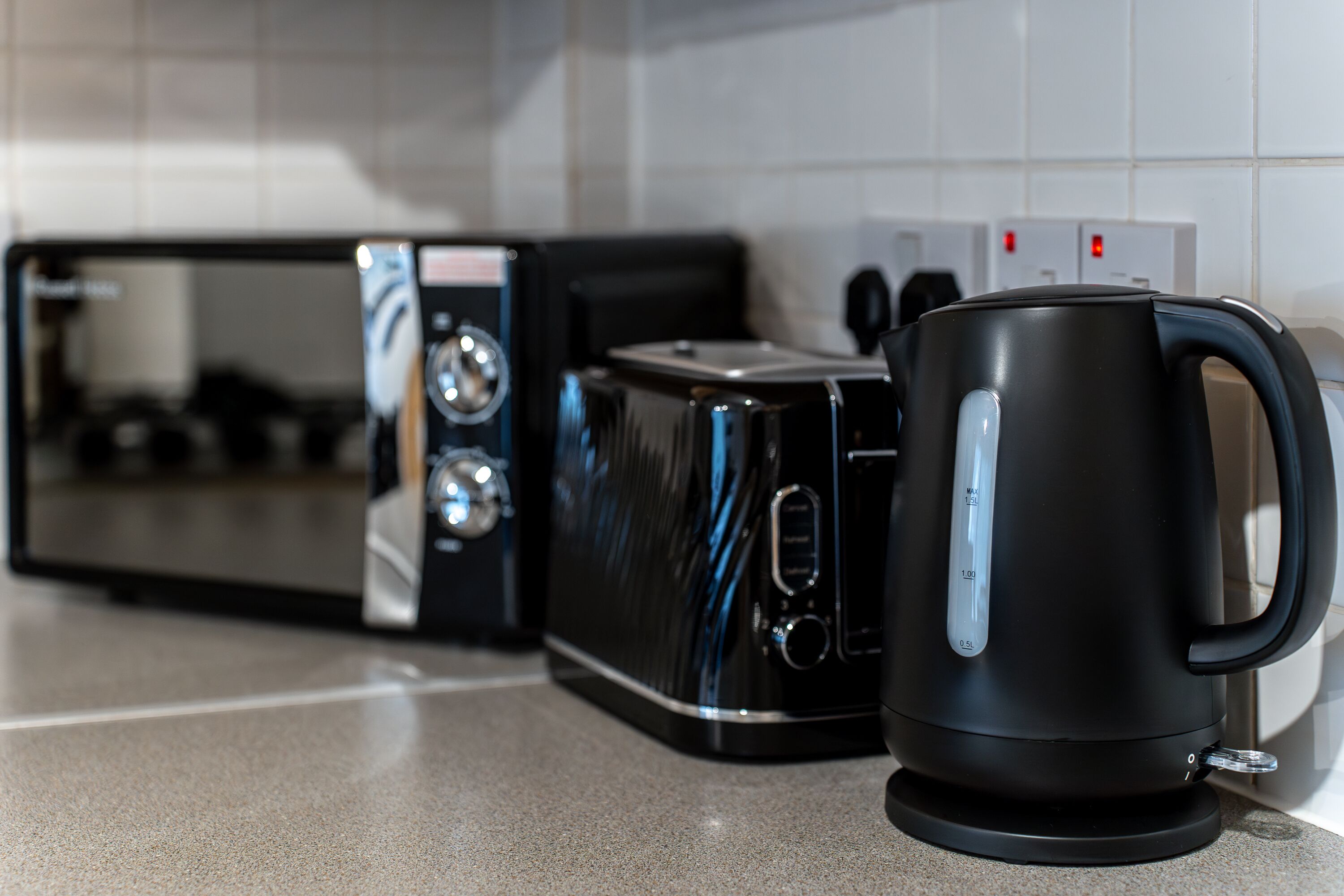 Una cocina con microondas, tostadora y cafetera sobre una encimera.