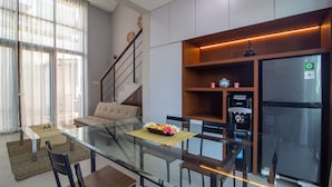 A modern kitchen with a glass dining table, wooden cabinets, and a stainless steel refrigerator. - Casa de Lily (Tabanan)