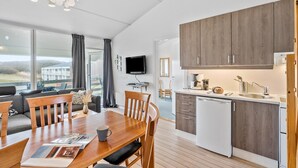 Een moderne keuken met houten kastjes, een inbouwvaatwasser en een eethoek met een houten tafel en stoelen.