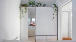 A bedroom with a sliding door closet, a bed, and a small window.