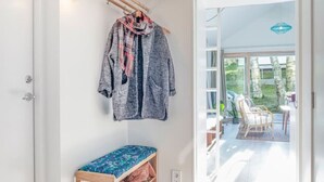 A hallway with a bench, a coat rack with a jacket, and a view of an outdoor patio area.