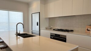 A modern kitchen with a large island, stainless steel appliances, and a minimalist design. - Casa Bianca - Ocean and harbour views (Cape Jaffa)