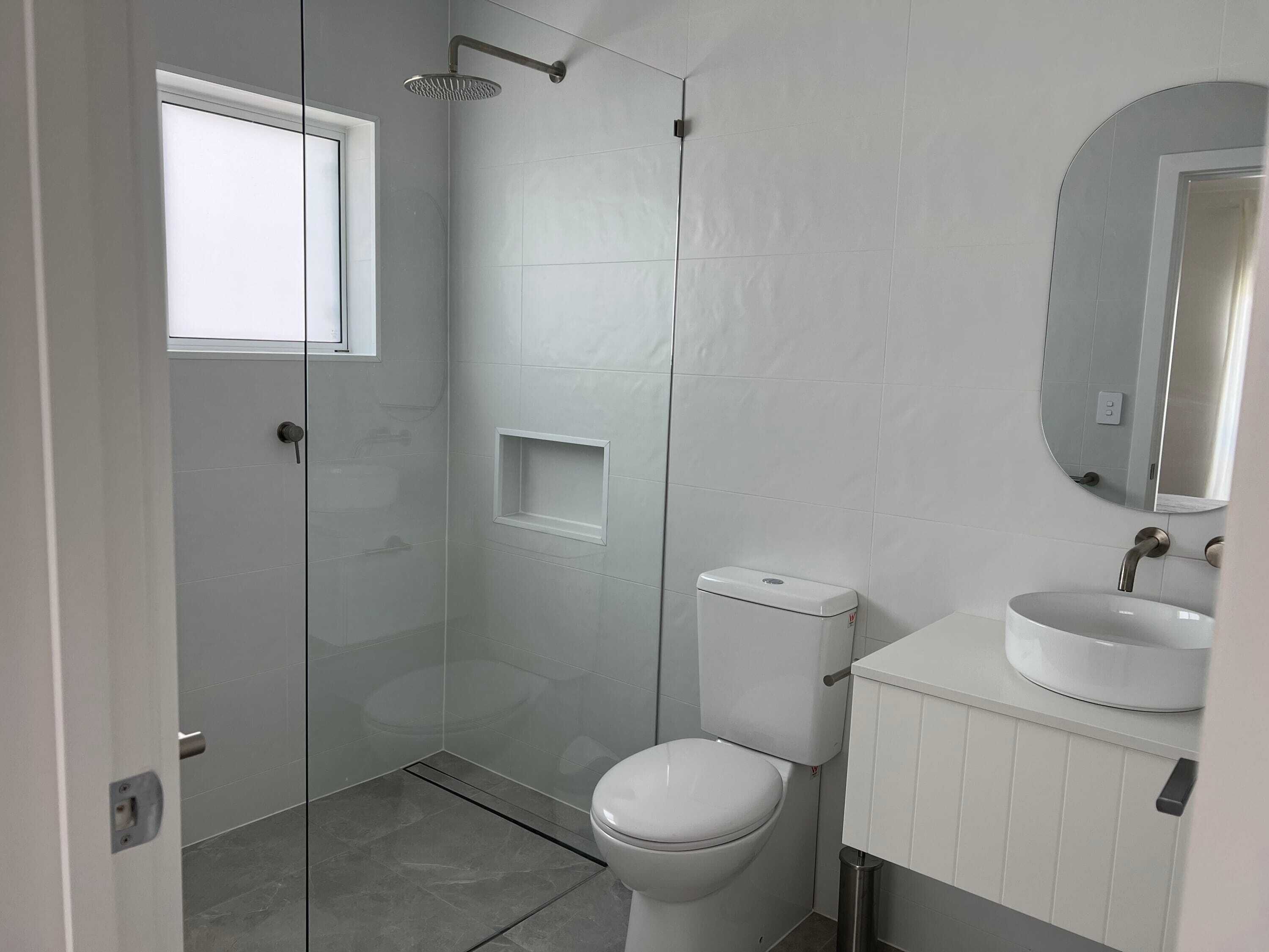 Une salle de bain avec des toilettes, un lavabo, une douche et une fenêtre.