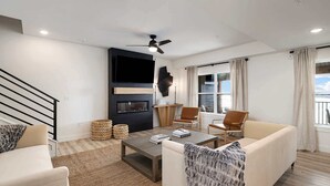 Een moderne woonkamer met een open haard, comfortabele zitplaatsen en een groot raam met uitzicht.