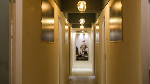 Un couloir agrémenté d’une œuvre d’art centrale, de deux suspensions lumineuses et d’un plancher poli.