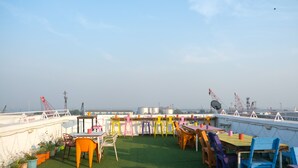 Une terrasse sur le toit, agrémentée d’une pelouse artificielle verdoyante, de chaises et de tables aux couleurs vives.