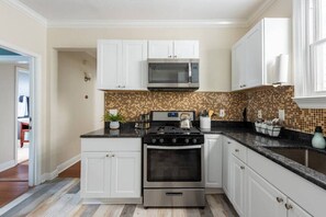 A kitchen with white cabinets, a stainless steel stove, and a microwave.