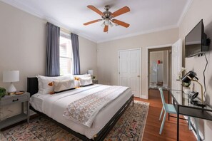 A bedroom with a bed, a desk, a chair, a ceiling fan, and a television. - Large Home w/ Back Yard Oasis | Perfect for Groups (New Orleans)