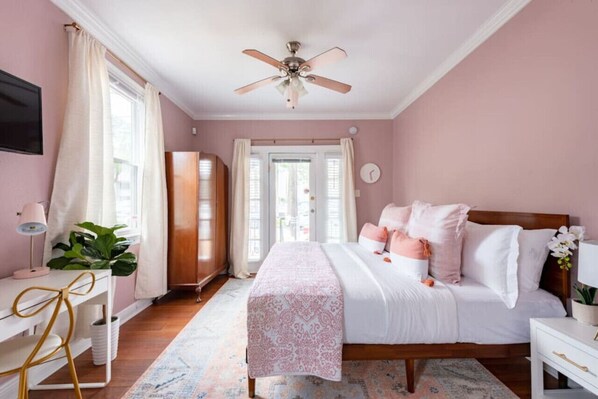A bedroom with a bed, bedside table, desk, chair, and a ceiling fan.