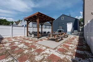 A backyard patio with a pergola, picnic tables, and a barbecue grill. - Large Home w/ Back Yard Oasis | Perfect for Groups (New Orleans)