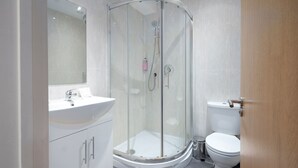 A modern bathroom with a glass-enclosed shower, a white sink, and a toilet.
