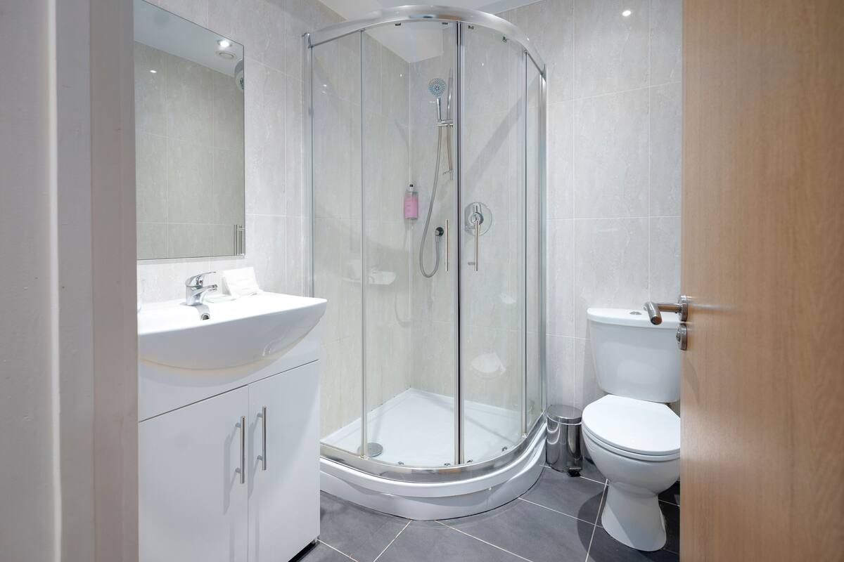 A modern bathroom with a glass-enclosed shower, a white sink, and a toilet.