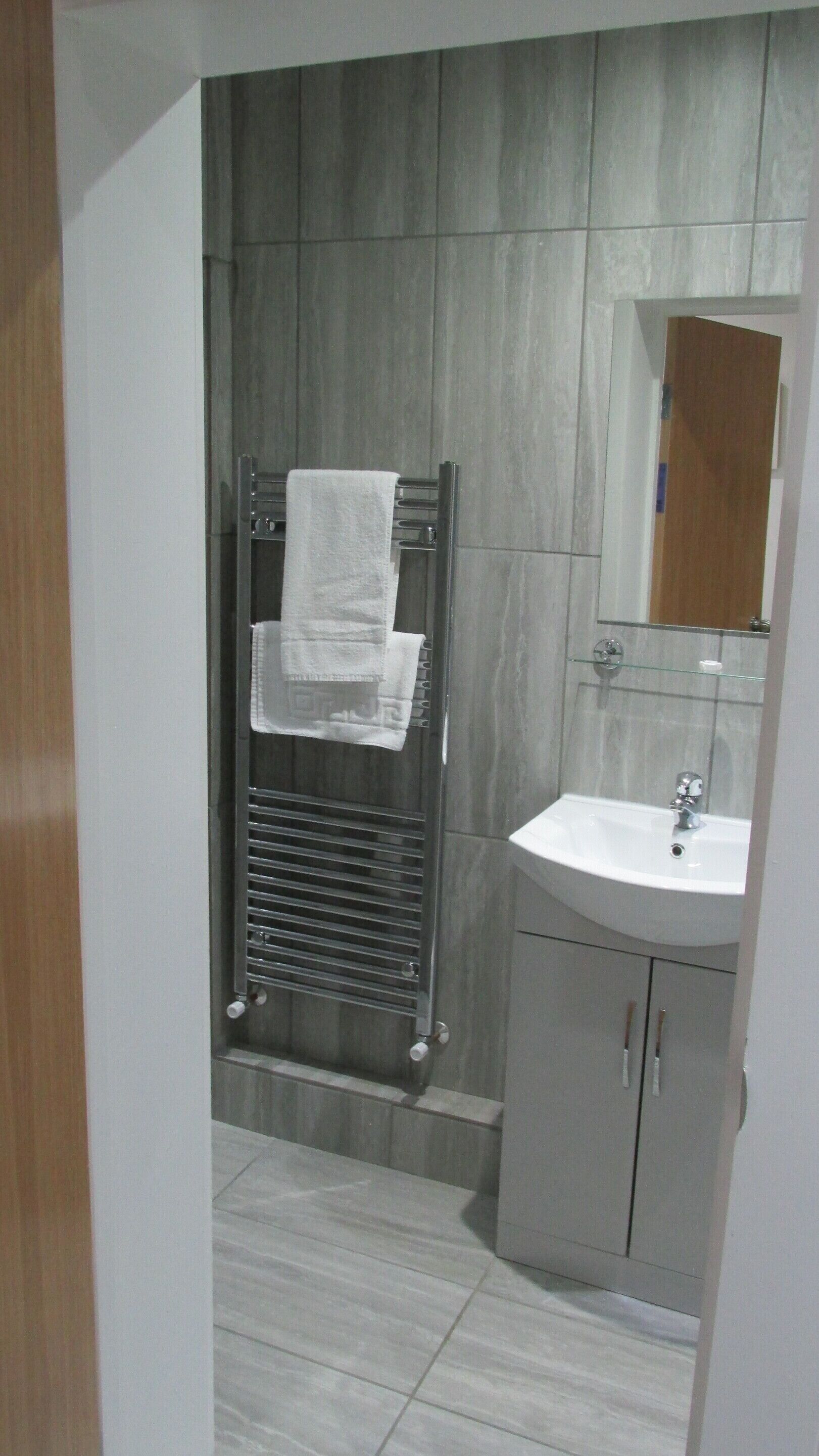 Een badkamer met een handdoekhouder, een wastafel en een spiegel.