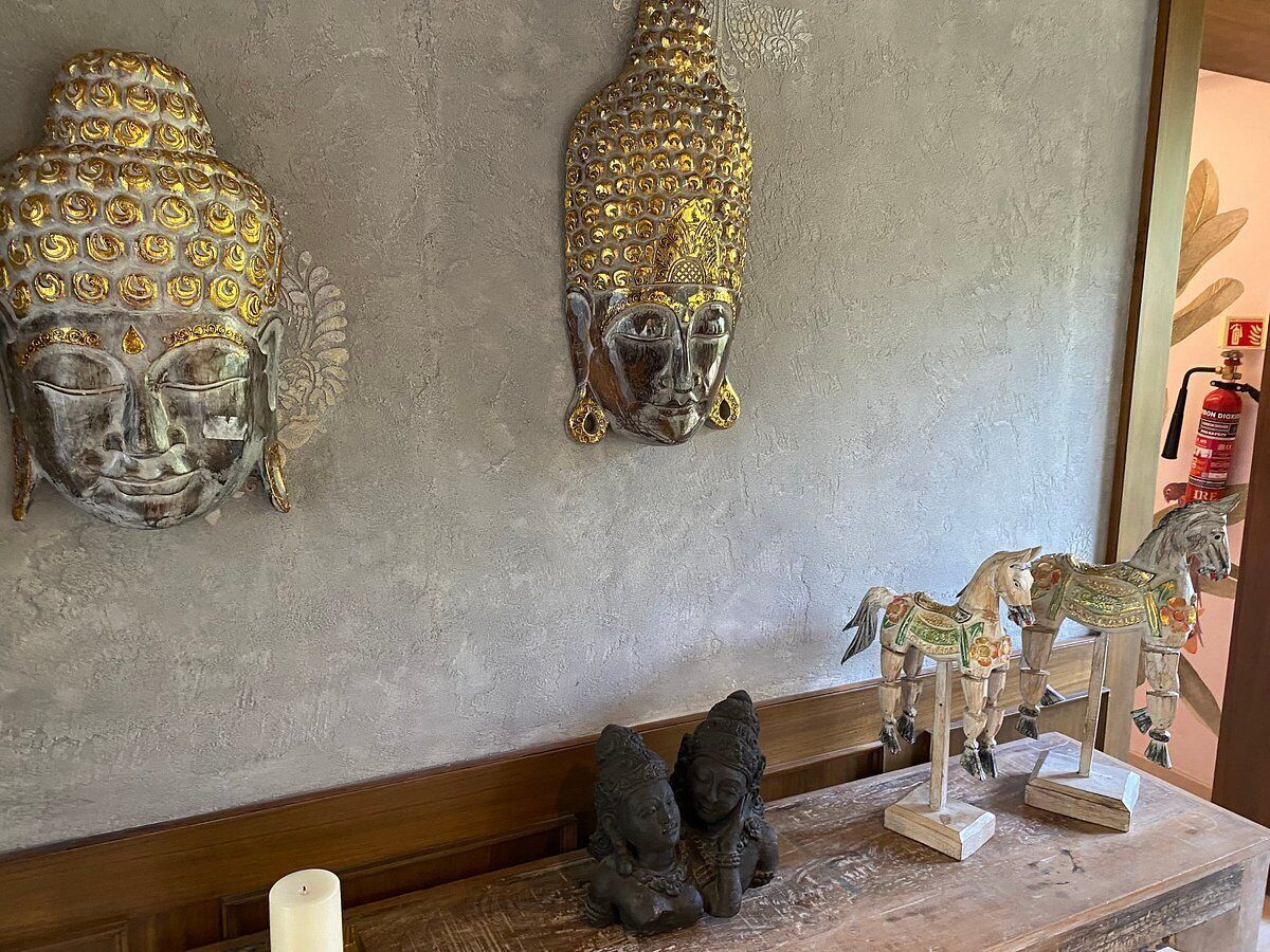 A room with a wooden bench, two Buddha statues, and a small altar with a candle.
