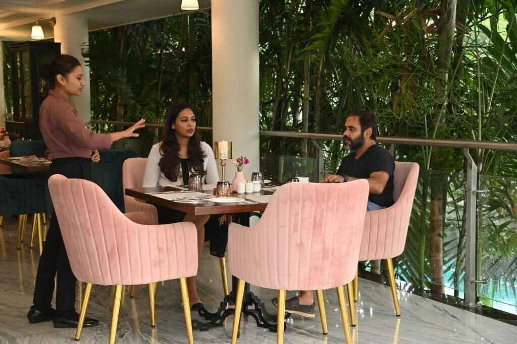 A dining area with a table set for four, surrounded by pink chairs with gold legs.