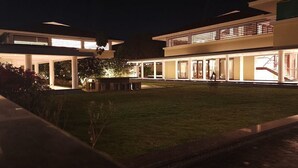A modern building with a well-lit exterior, large windows, and a spacious courtyard.