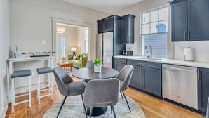 A modern kitchen with dark cabinets, a round dining table, and a small side table.