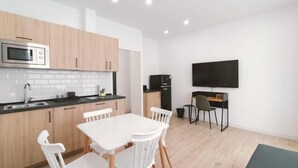 A modern kitchen with white cabinets, a microwave, and a dining area with a white table and chairs. - Apartamentos La Brava by gaiarooms  (Salamanca)