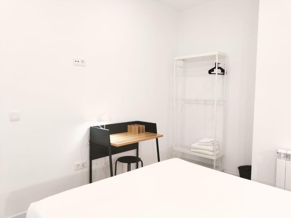 Un dormitorio minimalista con cama, escritorio y silla.