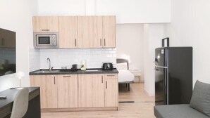 A compact kitchen with wooden cabinets, a microwave, a sink, and a refrigerator. - Apartamentos La Brava by gaiarooms  (Salamanca)