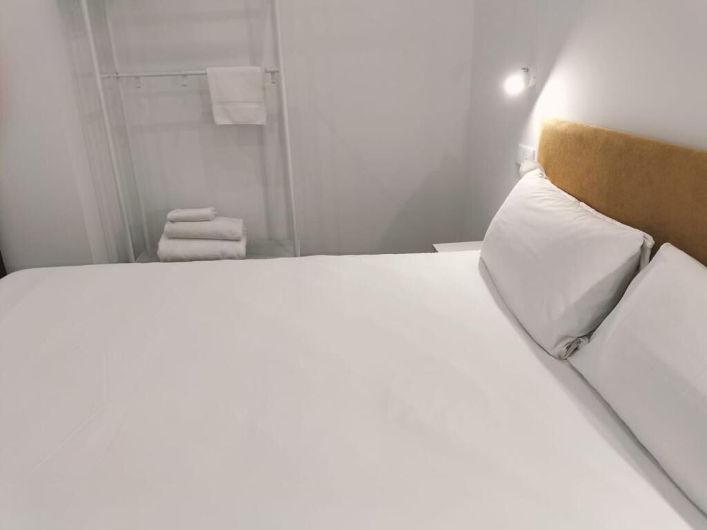 A hotel room with a bed, a headboard, and a shower area with towels.