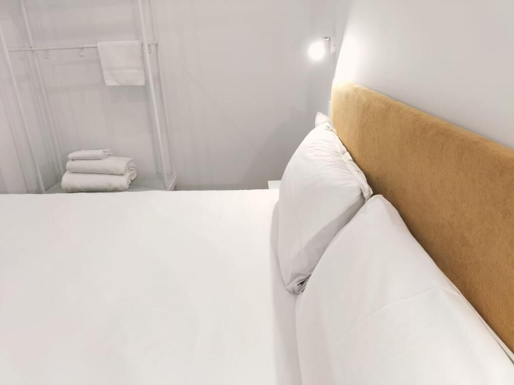 Une chambre d’hôtel avec un lit, du linge de lit blanc, une tête de lit et un espace douche équipé de serviettes.