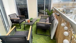 Un balcon doté d’un petit espace salon, comprenant une table et des chaises, ainsi qu’une plante en pot.
