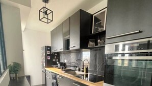 Une cuisine moderne avec des meubles noirs, un four en acier inoxydable et un plan de travail en bois.