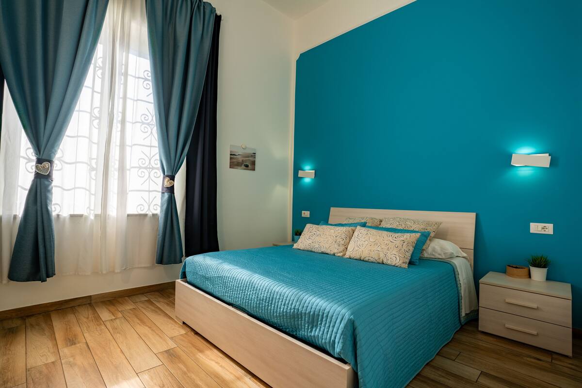 A bedroom with a bed, nightstands, and a window with curtains.