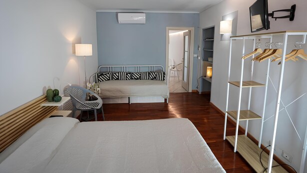 Ein Hotelzimmer mit Bett, Schreibtisch, Stuhl, Kleiderschrank und einem an der Wand befestigten Fernseher.
