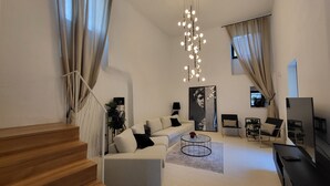 A modern living room with a staircase, a sofa, a coffee table, and a TV. - Casa Al Campanile for Your Relaxing Experience in a Rare Cocktail Pool (Vodnjan)