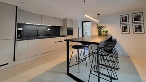 A modern kitchen with a black countertop, stainless steel appliances, and a bar area with stools. - Casa Al Campanile for Your Relaxing Experience in a Rare Cocktail Pool (Vodnjan)