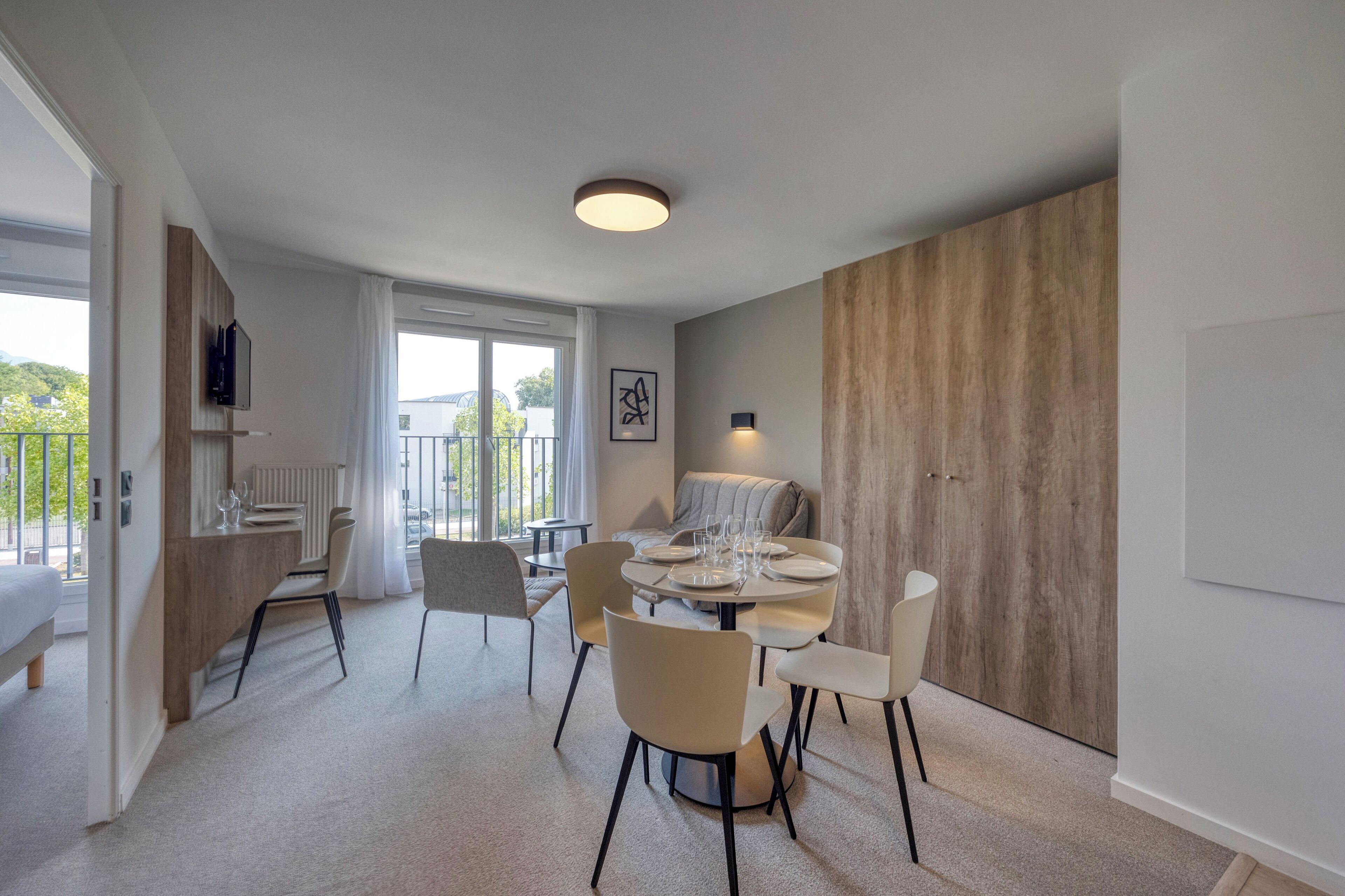 A modern dining area with a round table, chairs, and a sofa.