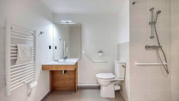 Un bagno moderno con il water bianco, un mobile lavabo in legno, uno specchio e uno spazio doccia con soffione manuale.